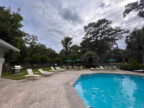 una piscina con sedie a sdraio e ombrelloni di 3 BR Villa Perfect for Families and Friends in Sea Pines, Hilton Head a Hilton Head Island