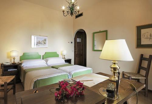 a bedroom with a bed and a table with a lamp at Hotel Villa Sirina in Taormina
