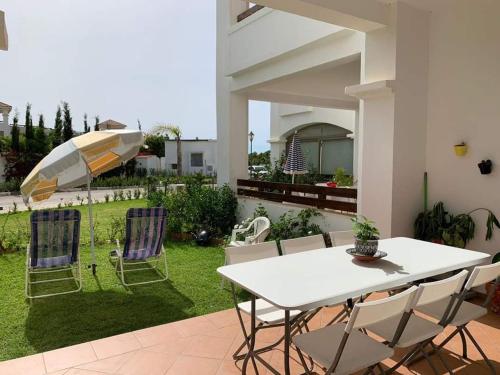 a patio with a table and chairs and an umbrella at Beralmar Asilah Chez FATIMA in Asilah