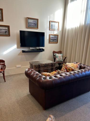 a living room with a brown leather couch and a television at Poshtel in Oamaru