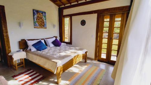 1 dormitorio con 1 cama con almohadas azules en Sitio Boa Fé - 300m das cachoeiras Moinho e Salomão en Carrancas