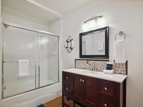 uma casa de banho com um chuveiro, um lavatório e um espelho. em Amigo Bay em Galveston