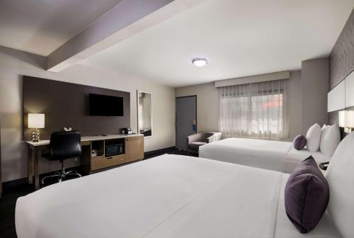 ロサンゼルスにあるSunset West Hotel, SureStay Collection By Best Westernのベッド2台、薄型テレビが備わるホテルルームです。