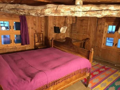 a bedroom with a wooden bed in a room with windows at Posta Veglia in Sils Baselgia