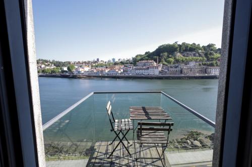 a balcony with two chairs and a table on the water at Douro Destilaria Residence by Porto City Hosts in Vila Nova de Gaia