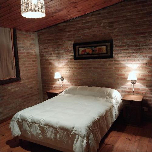 a bedroom with a white bed and two night tables at La Quina. in Villa Rumipal