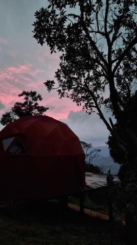a red tent sitting next to a tree at Cabanas Bela Vista in São Bento do Sapucaí