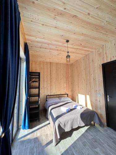 a bedroom with a bed in a room with wooden walls at Cottage Orcs in Borjomi
