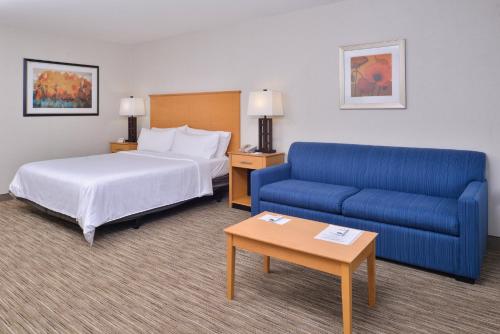 ein Hotelzimmer mit einem Bett und einem blauen Sofa in der Unterkunft Holiday Inn Express Stockton Southeast, an IHG Hotel in Stockton