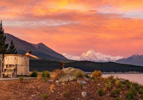 a person jumping off the side of a building with mountains in the background at Mt Cook Lakeside Retreat in Lake Pukaki