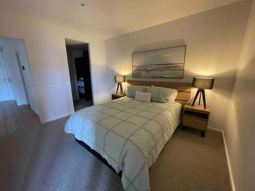 1 dormitorio con 1 cama con 2 lámparas y una pintura en la pared en Modern luxurious unit in the heart of Dickson en Canberra