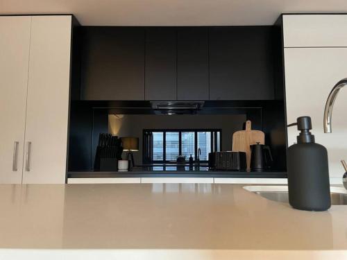 una cocina con armarios negros y una botella en una encimera en Modern luxurious unit in the heart of Dickson en Canberra