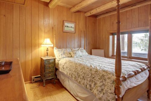 una camera da letto con pareti in legno, un letto e una finestra di Lakefront Fence Home with Private Hot Tub! 