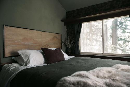 1 dormitorio con 1 cama y ventana grande en Mountain Hut Myoko, en Myoko