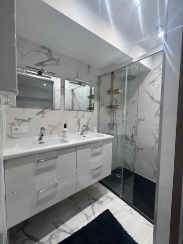 a white bathroom with a sink and a shower at Appartement spacieux et agréable in Callian
