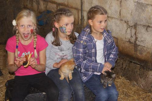three girls sitting next to a wall holding kittens at Der Perweinhof in Donnersbachwald