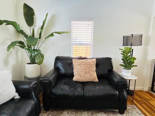 a black leather couch in a living room with two plants at Home Sweet Idahome, feels like home with all the decor you wish you could afford King bed in master, fully fenced dog friendly yard, a few blocks from BSU and downtown Boise, Your perfect stay! in Boise