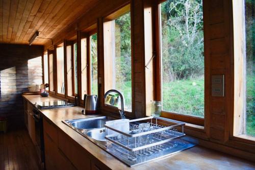 eine Küche mit einer Spüle und einer Theke mit Fenstern in der Unterkunft Refugio Arquitectónico frente al Mar in Ancud