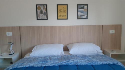 a bedroom with a bed with two pillows and pictures on the wall at Aconchego no centro de Poços! in Poços de Caldas