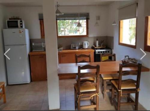 cocina con mesa, sillas y nevera en Casa Catedral Bariloche en San Carlos de Bariloche