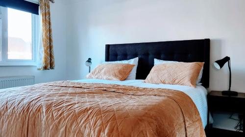 1 dormitorio con 1 cama grande con sábanas y almohadas de color naranja en Family friendly spacious 4bedroom house in Bagshot with EV Charger en Bagshot