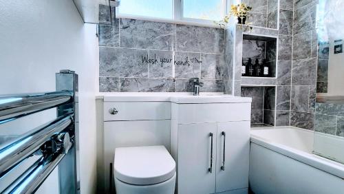 a bathroom with a toilet and a sink and a tub at Family friendly spacious 4bedroom house in Bagshot with EV Charger in Bagshot