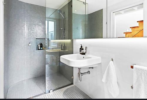 ein weißes Bad mit einem Waschbecken und einer Dusche in der Unterkunft Cosy Cottage 2 Bedroom Great Location Close to Transport in Sydney