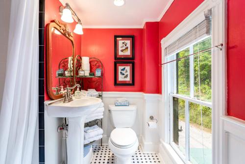 a bathroom with red walls and a toilet and a sink at Enchanting Cottage, Center of Historic Downtown! in Harpers Ferry