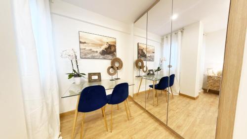 a dining room with a glass table and blue chairs at Paradise Luxurious apartment, 3 double rooms for 6 guests, 4 beds, terrace, jacuzzi, free parking, new in Donostia-San Sebastián