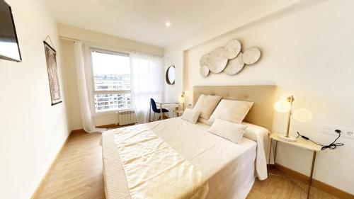 een witte slaapkamer met een groot bed en een raam bij Paradise Luxurious flat, free parking, 3 double rooms, terrace, jacuzzi, fully renovated in San Sebastian