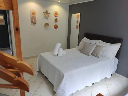 um quarto com uma cama branca com duas velas em Lopes House Araçatiba em Praia de Araçatiba