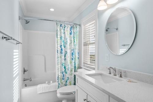 een badkamer met een wastafel, een toilet en een spiegel bij Poseidon in Atlantic Beach