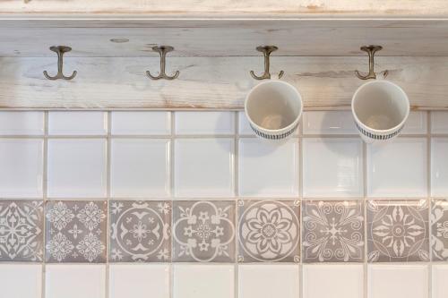 two mugs are hanging on a wall with tiles at Florence Holiday Homes Santa Maria Novella in Florence