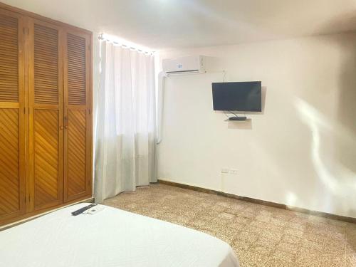 a bedroom with a bed and a tv on the wall at Sweet Home RIOHACHA in Ríohacha