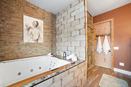 La salle de bains est pourvue d'une grande baignoire blanche à côté d'un mur en briques. dans l'établissement Chicago Mid-Century Gem Steps From United Center, à Chicago