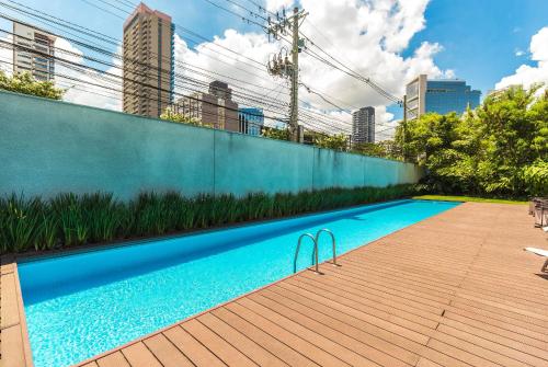 a swimming pool next to a fence with tall buildings at Triplo in Sao Paulo