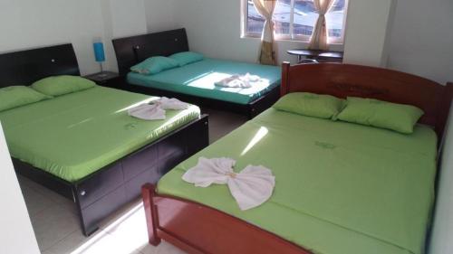 a room with two beds with green sheets at Hotel Boutique San Juan in Neiva