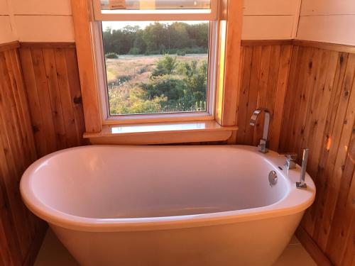uma banheira na casa de banho com uma janela em MareGold Centre - Juniper Cabin and Rose Cabin em Victoria Beach 