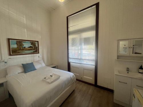 1 dormitorio con cama, lavabo y ventana en The Australian Hotel, en Gympie