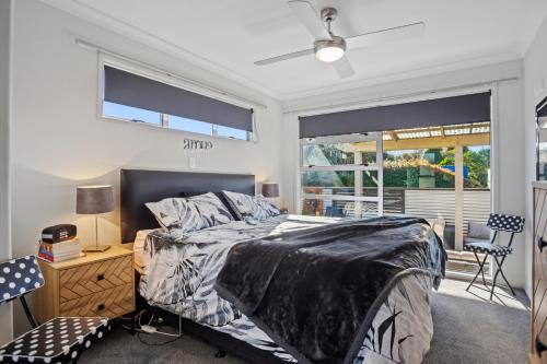 een slaapkamer met een bed, een bureau en een raam bij Tui's Rest - Waihi Beach Holiday Home in Waihi Beach