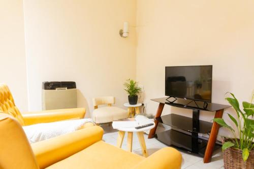 sala de estar con muebles de color amarillo y Tv LED. en Alojamiento Ideal en Ciudad de Mendoza - Amplio y bien ubicado en Mendoza