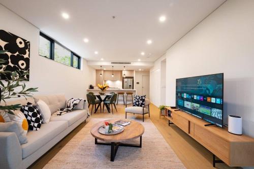a living room with a couch and a tv at Le Soleil The Sun-Inspired Luxury Apartment in Sydney
