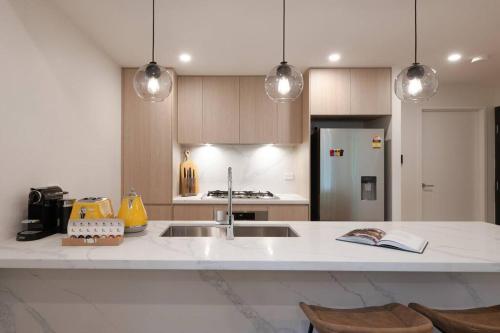 a kitchen with a sink and a counter with chairs at Le Soleil The Sun-Inspired Luxury Apartment in Sydney