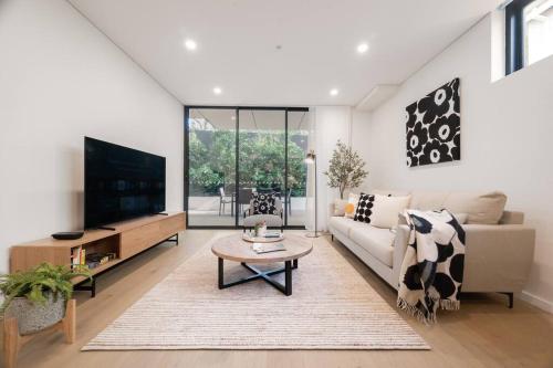a living room with a couch and a tv at Le Soleil The Sun-Inspired Luxury Apartment in Sydney