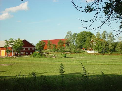 a large field with a red barn and a farm at Sundsmåla Landsbygdshotell in Brokind