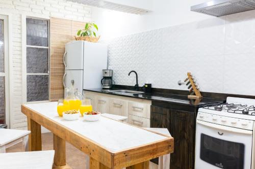 cocina con mesa de madera y nevera blanca en La Casita de Paso de los Andes, Mendoza, en Mendoza