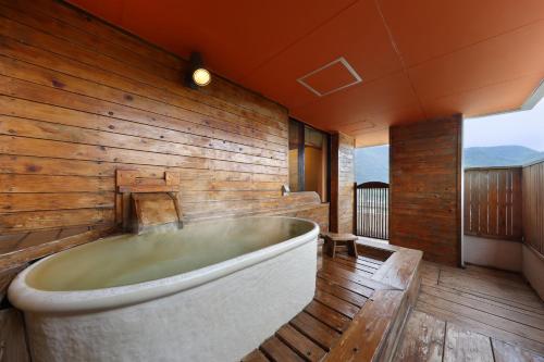 bañera en una habitación con pared de madera en Hotel Sunshine Kinugawa, en Nikko