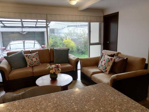 a living room with two couches and a table at Hermosa y confortable suite in Quito