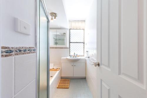 a white bathroom with a sink and a shower at Fleetwood 4 Air conditioned unit with water views in Shoal Bay