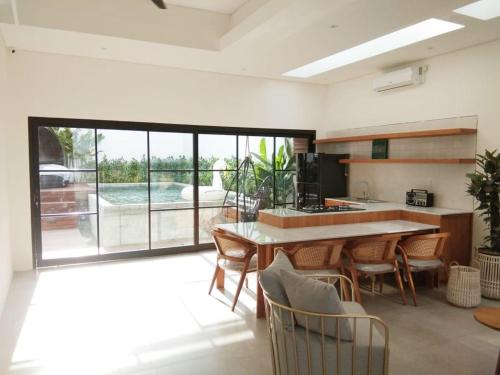 eine Küche mit Tisch und Stühlen und einem großen Fenster in der Unterkunft Villa Maitreya in Uluwatu